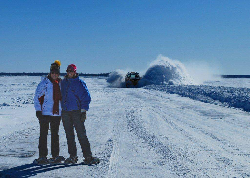 Two Women with Snow Plow in Background